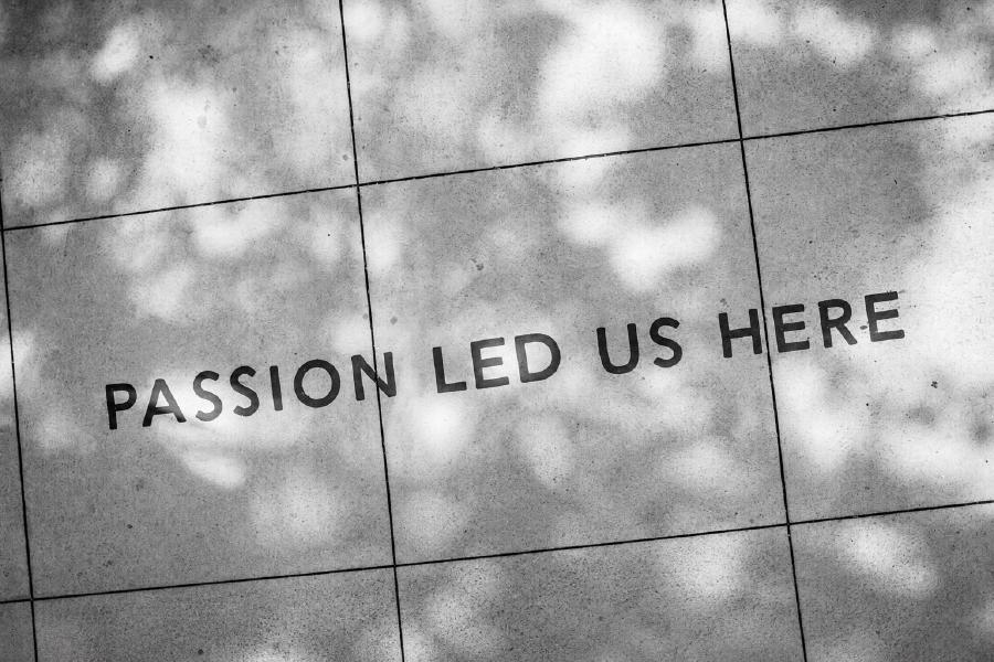 Two people standing beside the words Passion Led Us Here